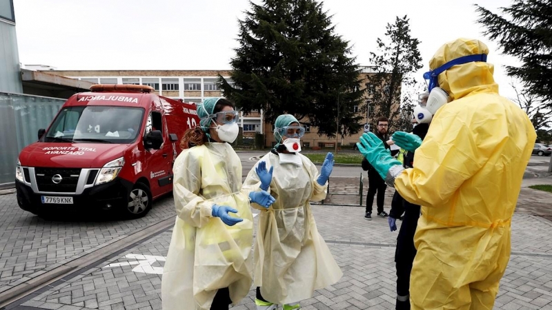 Dos enfermeras que acaban de trasladar en ambulancia a un enfermo que ha dado positivo en el test del COVID-19 solicitan ayuda de un efectivo de la DYA Navarra que en coordinación con el departamento de Salud ha implantado un túnel de desinfección en el C