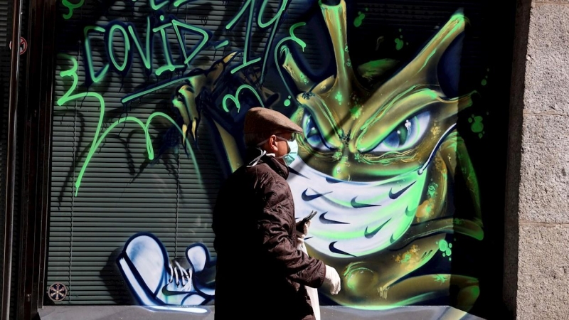 Una persona pasa por una calle de Salamanca en la que han realizado un graffiti con el tema del COVID-19. EFE/J.M.GARCIA