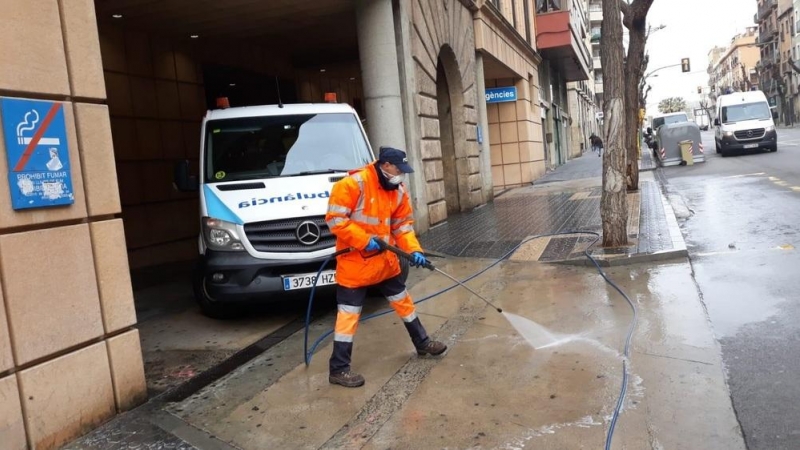 Un treballador netejant amb aigua a pressió davant l'accés a l'hospital de Sant Pau i Santa Tecla de Tarragona.