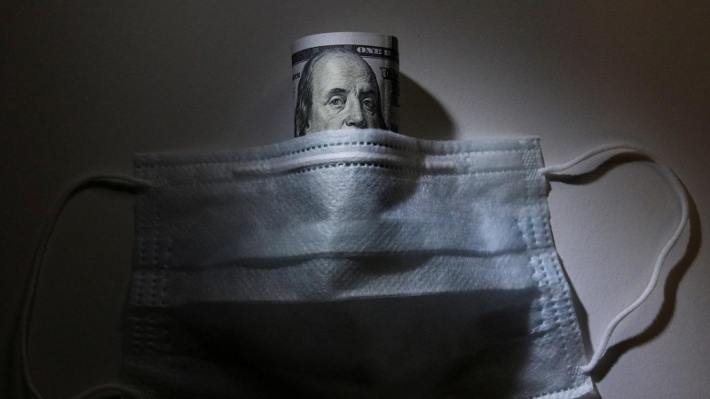 24/03/2020 - Un billete de dólar y una mascarilla. / REUTERS - Alexey Pavlishak