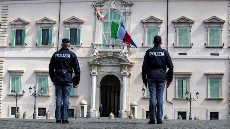 Dos agentes de policía observan la bandera italiana y la de la Unión europea (UE) a media asta, este martes en el Palacio del Quirinal, en Roma (Italia).  | EFE