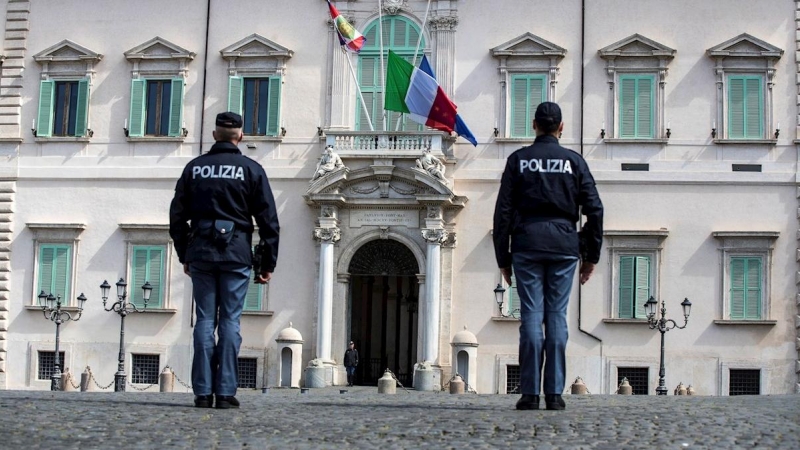 Dos agentes de policía observan la bandera italiana y la de la Unión europea (UE) a media asta, este martes en el Palacio del Quirinal, en Roma (Italia).  | EFE