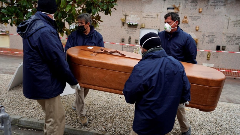 Los empleados de una morgue llevan el ataúd de una persona que murió por la enfermedad del coronavirus (COVID-19), durante el cierre parcial para combatir el brote de la enfermedad, en el cementerio de Carabanchel en Madrid, España, el 27 de marzo de 2020