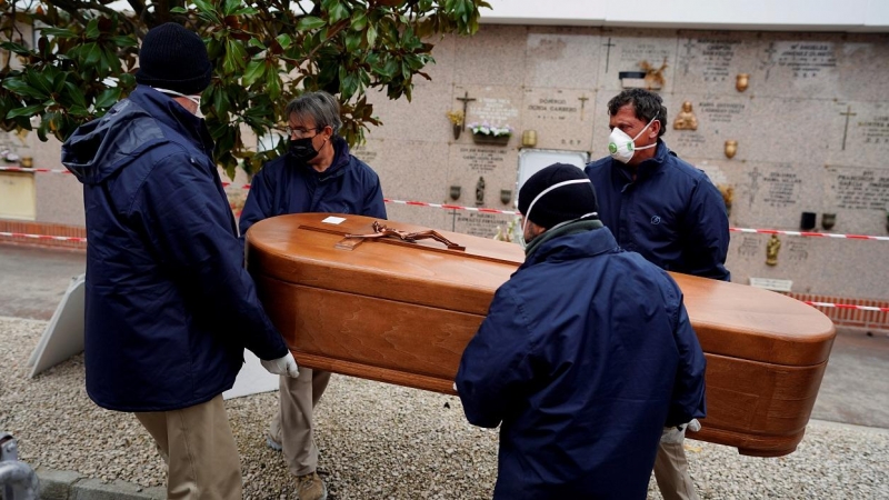 Los empleados de una morgue llevan el ataúd de una persona que murió por la enfermedad del coronavirus (COVID-19), durante el cierre parcial para combatir el brote de la enfermedad, en el cementerio de Carabanchel en Madrid, España, el 27 de marzo de 2020