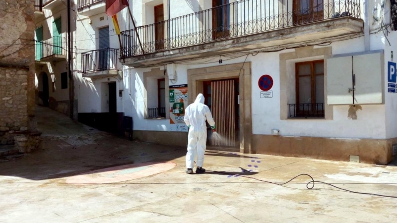 Pla general d'un operari de la Diputació de Tarragona desinfectant la plaça major de Paüls, a les portes de l'Ajuntament. ACN.