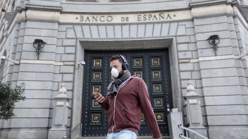 Un hombre con una mascarilla pasa junto a las oficinas del Banco de España, en Barcelona. REUTERS/Nacho Doce