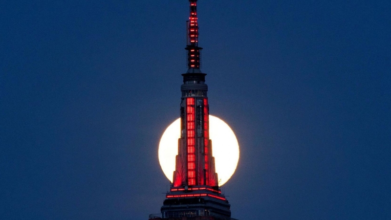 La superluna rosa se eleva detrás del Empire State Building mientras se ilumina en rojo en solidaridad con las personas infectadas con el coronavirus.  REUTERS/Eduardo Munoz