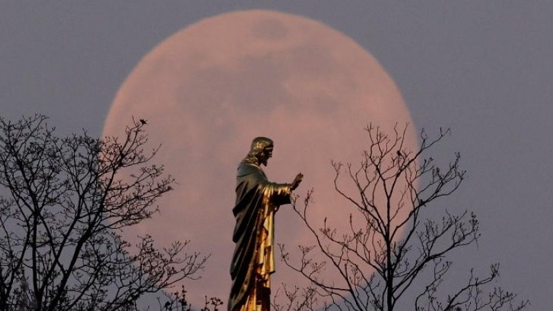 La superluna rosa se eleva detrás de la estatua del Sacré-Coeur du Horn que representa la figura de Cristo durante la Semana Santa en Wolxheim, cerca de Estrasburgo. REUTERS / Christian Hartmann