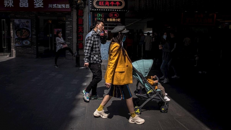 Las personas usan mascarillas mientras caminan en un área comercial en Wuhan, China, el 06 de abril de 2020. EFE / ROMAN PILIPEY