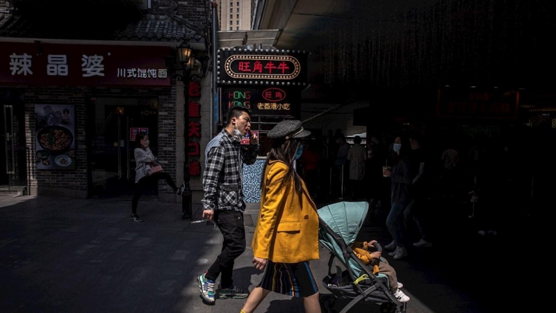 Las personas usan mascarillas mientras caminan en un área comercial en Wuhan, China, el 06 de abril de 2020. EFE / ROMAN PILIPEY