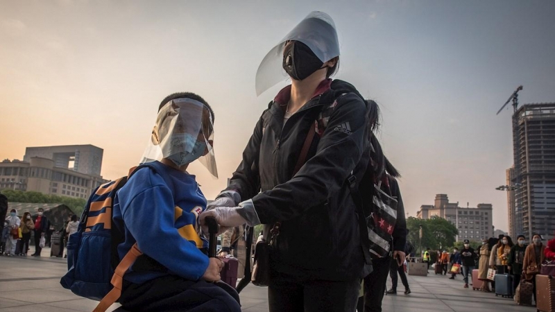 Los pasajeros que usan engranajes protectores esperan para ingresar a la estación de ferrocarril después de que se levantó el bloqueo, en Wuhan, China. EFE / ROMAN PILIPEY