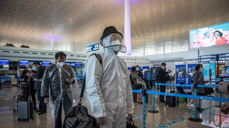 Los pasajeros con equipo de protección esperan en el aeropuerto internacional de Wuhan Tianhe después de que se levantó el bloqueo en Wuhan, China, el 8 de abril de 2020. EFE / ROMAN PILIPEY