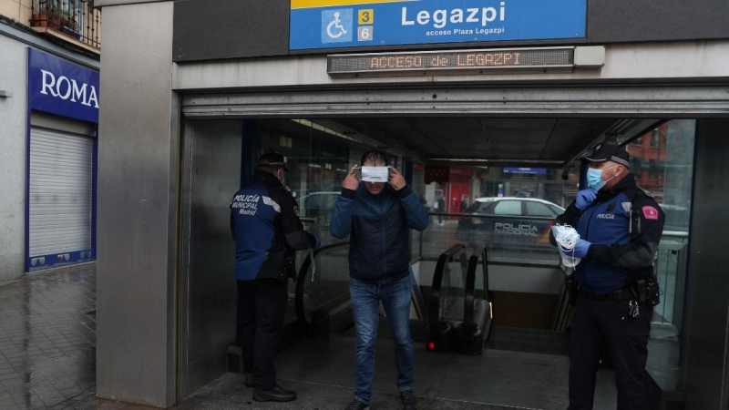 Un hombre intenta ponerse una mascarilla protectora mientras sale de una estación de metro durante el encierro en medio del brote de la enfermedad del coronavirus en Madrid. REUTERS / Susana Vera