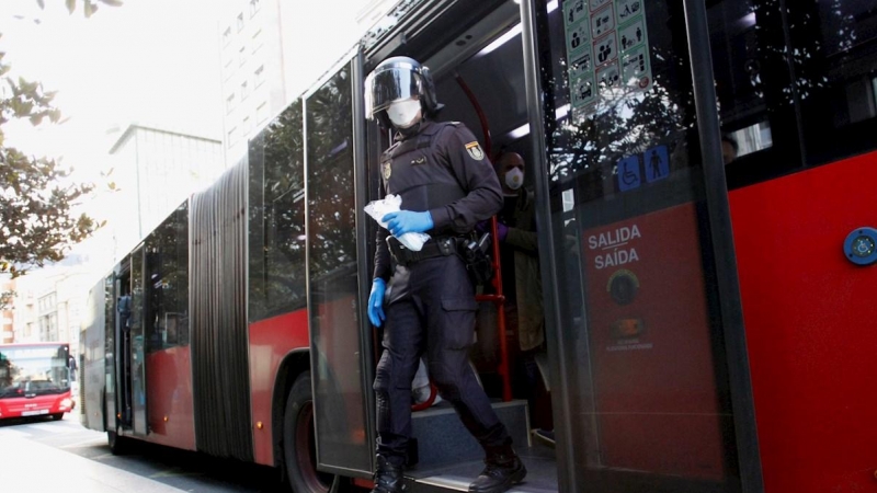 Miembros de la policía efectúa el reparto de mascarillas en el transporte público en A Coruña este lunes, primera jornada para muchos ciudadanos que regresan a sus trabajos tras el fin de la restricción a las actividades económicas no esenciales, en la qu