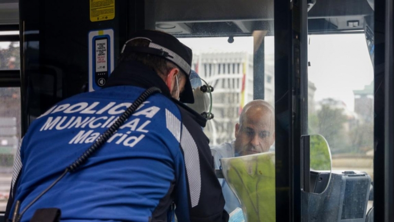 Un agente de la Policía Municipal de Madrid reparte mascarillas a los pasajeros de un autobús de la línea 9 de la EMT el día en el que se reactiva la actividad laboral no esencial. Europa Press / Ricardo Rubio