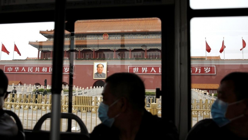 Personas con mascarilla pasan en un autobús por delante de la Ciudad Prohibida, en la Plaza de TTiananmen, en Pekín.. REUTERS/Tingshu Wang