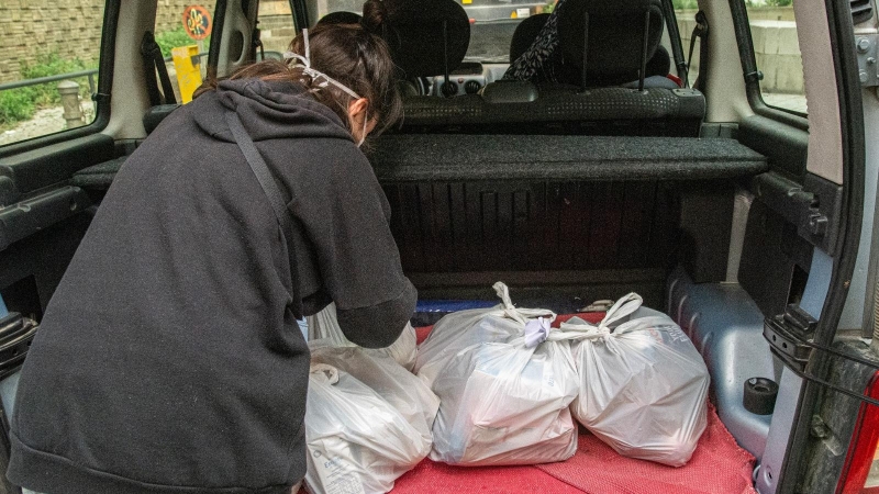 Una voluntaria carga el maletero con bolsas de alimentos básicos antes de salir al reparto entre los hogares que las necesitan.-MANU MITRU (CEDIDA)