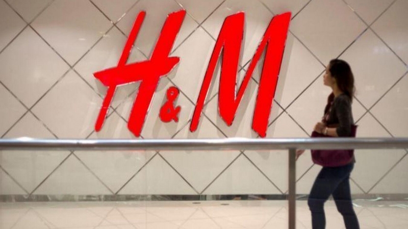 Una mujer, caminando junto al logotipo de H&M. /EFE
