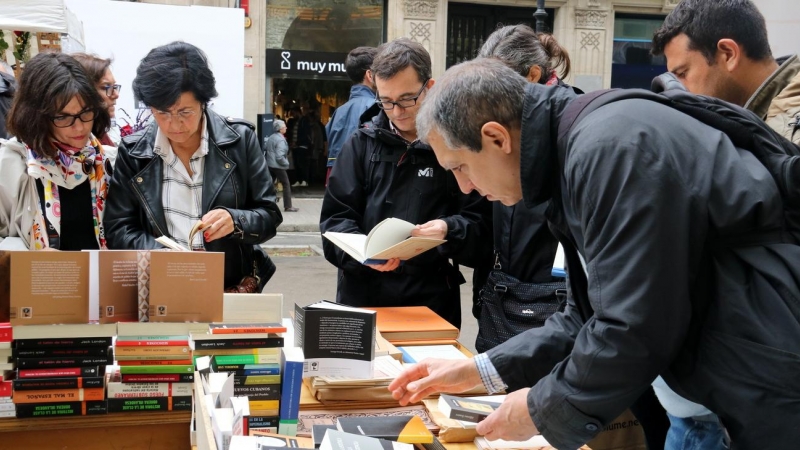 Lectors remenen llibres a una parada de la Rambla de Catalunya de Barcelona durant el dia de Sant Jordi. Imatge del 23 d'abril de 2019. (Horitzontal). ACN | Mar Vila