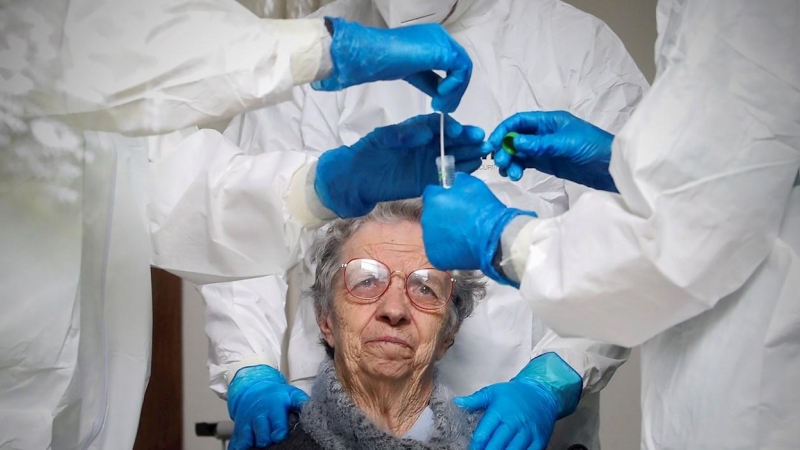 Un mujer observa al personal sanitario tras hacerse una prueba de coronavirus en la Fundación Comendador Joaquim De Sa Couto Foundation en Santa Maria da Feira, Portugal. EFE/ Jose Coelho