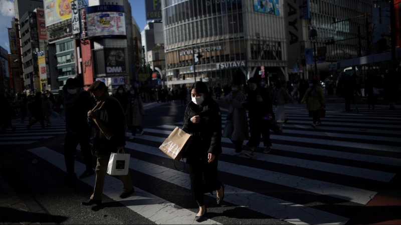 Una mujer con mascarilla cruza la calle  en el barrio de Shibuya, la principal zona comercial de Tokio. REUTERS/Stoyan Nenov