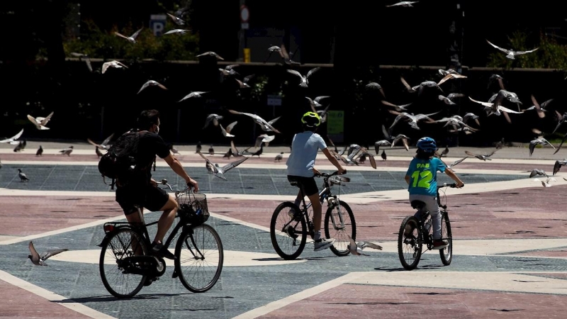 Dos niños y un adulto pasean en bicicleta por la Plaza de Catalunya de Barcelona este martes, cuando se cumplen 45 días de confinamiento por el estado de alarma decretado por el Gobierno por la crisis del coronavirus. EFE/Enric Fontcuberta