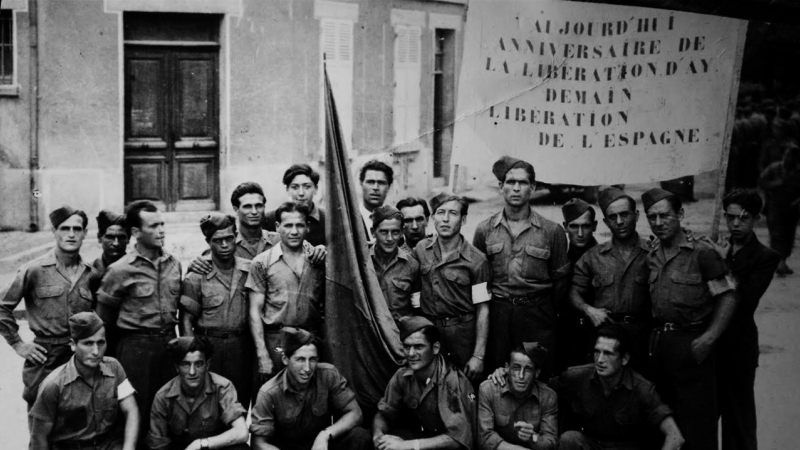 En 1945, la ciudad francesa de Ay recibió a un grupo de deportados españoles. Entre ellos, estaba Juan Romero Romero. En la pancarta expresan su deseo de la pronta liberación de España de la dictadura de Franco.- DEPORTADOS.ES