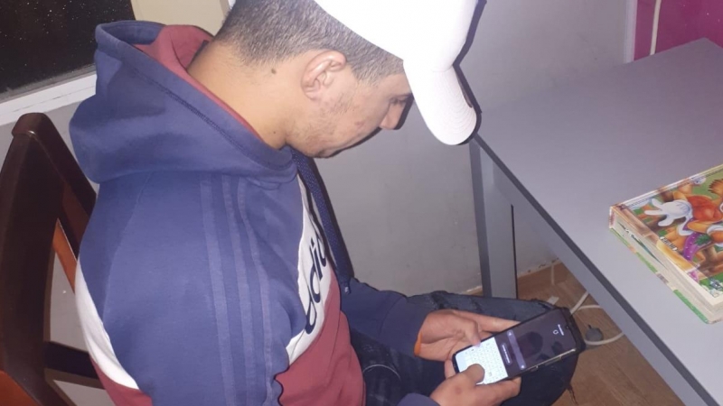 Ahmed, en casa, usando el teléfono para conectarse con su familia