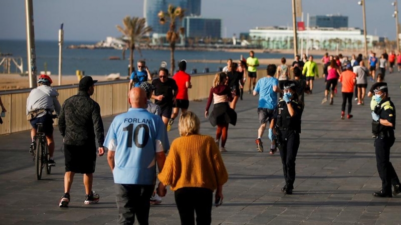 Policías municipales observan a los ciudadanos que dan un paseo o hacen ejercicio por el Paseo Marítimo de Barcelona, este sábado./ Quique García (EFE)
