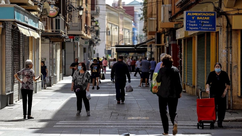 Ciudadanos con mascarillas paseando por una calle de València. /EFE