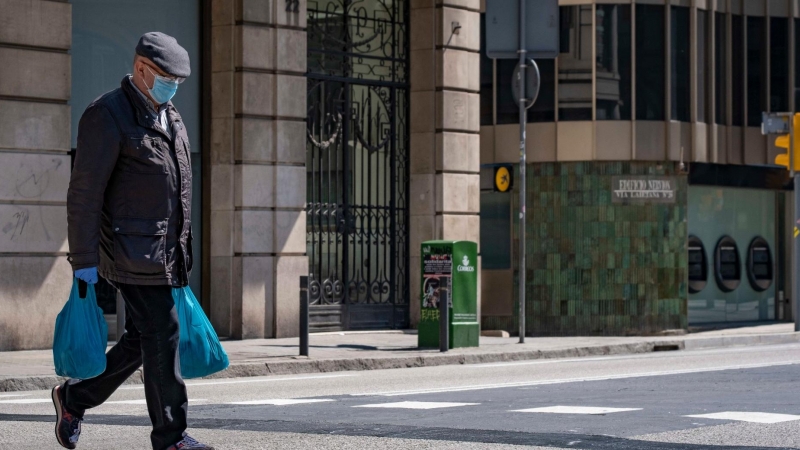 Un home que porta borses de la compra camina en la deserta Via Laietana causa de les mesures de confinament. Foto: Paco Freire/SOPA/ DPA/ Europa Press