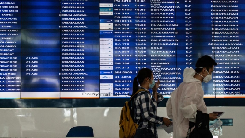 Pasajeros de China pasan junto al monitor que confirma la cancelación de todos los vuelos, en el Aeropuerto Internacional de Sukarno Hatta. / Europa press