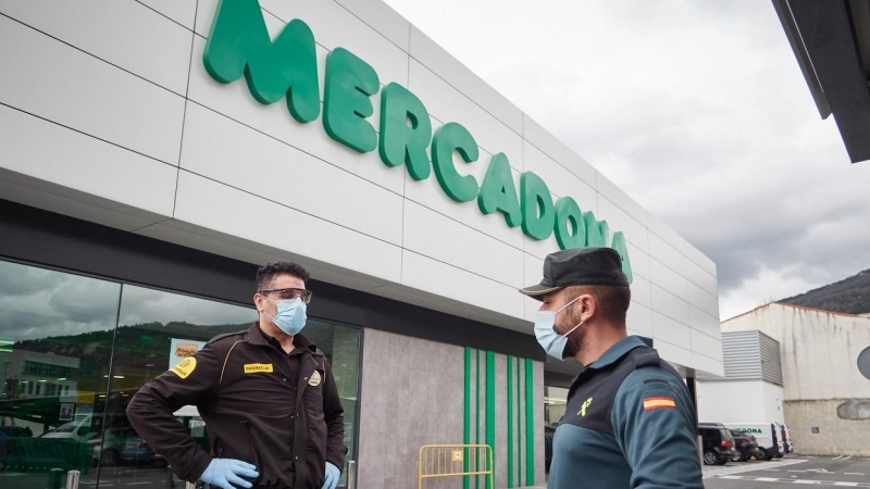 Un vigilante jurado y un guardia civil, ambos con mascarillas, delante de una tienda de Mercadona en Pamplona. E.P./Eduardo Sanz