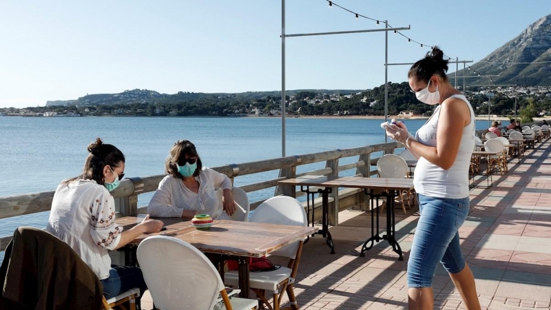 Una camarera atiende a dos clientas en una terraza en la localidad Alicantina de Denia, uno de los territorios de España que comienza la Fase 1.EFE/ Juan Carlos Cárdenas