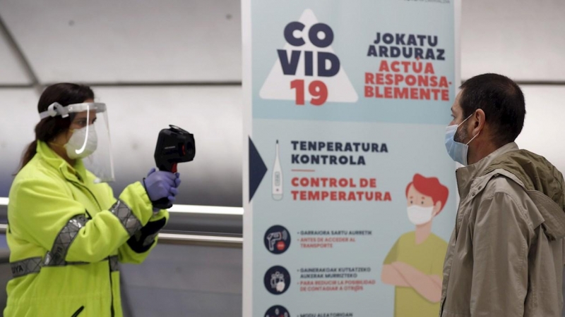 Una voluntaria de la DYA toma la temperatura a una viajero antes de embarcar en una unidad del metro de Bilbao. EFE/LUIS TEJIDO.