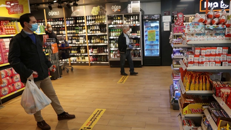 Clientes, con mascarillas, guardan la distancia social esperando a pasar por caja de un supermercado Dia&Go, del Grupo Dia, en Madrid. REUTERS/Susana Vera