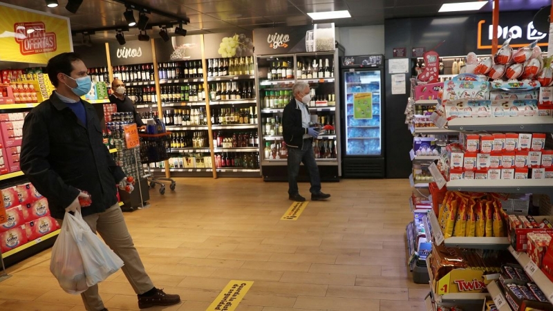 Clientes, con mascarillas, guardan la distancia social esperando a pasar por caja de un supermercado Dia&Go, del Grupo Dia, en Madrid. REUTERS/Susana Vera