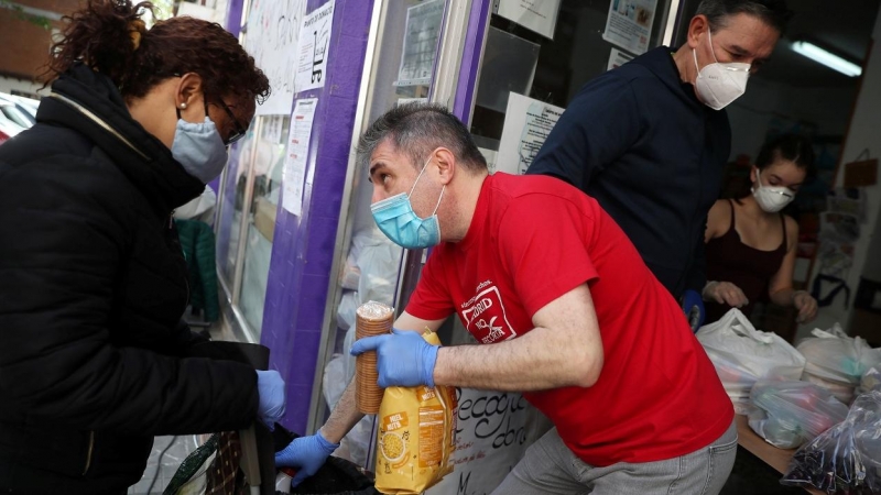 Una mujer recibe alimentos donados por voluntarios de la asociación Vecinos Parque Aluche, en Madrid, durante el estado de alarma por la pandemia del coronavirus. REUTERS / Susana Vera