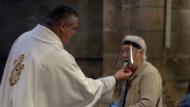 11/05/2020.- Una mujer comulga durante la celebración de misa en el interior de la catedral de Ourense. / EFE - BRAIS LORENZO