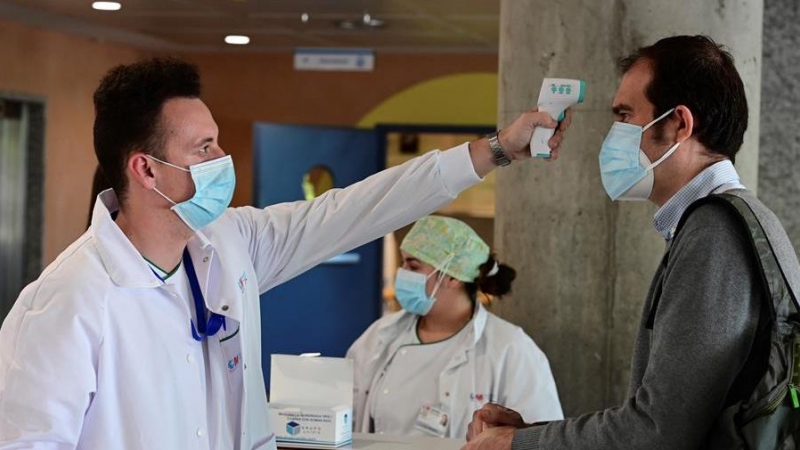 Un sanitario toma la temperatura a un hombre que accede al Hospital de Alcorcón en Madrid, este lunes. EFE/Víctor Lerena