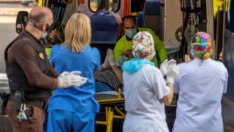 Un paciente que baja de una ambulancia participa en el apluaso al personal sanitario y de seguridad del hospital Virgen de la Salud de Toledo este domingo. Los sanitarios han agradecido el apoyo de los ciudadanos que se han acercado convocados a través de