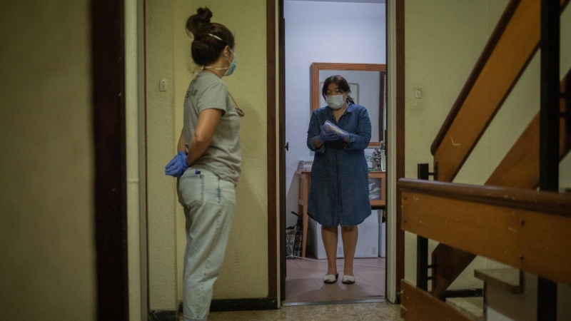 Una voluntària de l'ONG Proactiva Open Arms lliura a una dona material sanitari en plena crisi de la Covid-19. David Zorrakino / Europa Press