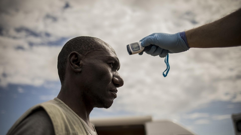 Un voluntario de la ONG Medicos del Mundo mide la temperatura de un migrante que vive en un asentamiento informal Níjar, Almería. Según esta organización, que realiza un seguimiento en estos campamentos, el sistema sanitario no tiene de momento ningún pla