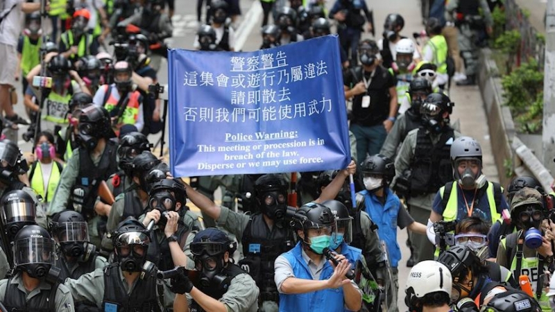 Los agentes de la policía antidisturbios llevan una pancarta que advierte a los manifestantes que se dispersen durante una manifestación contra la implementación de una nueva ley de seguridad nacional. EFE / JEROME FAVRE