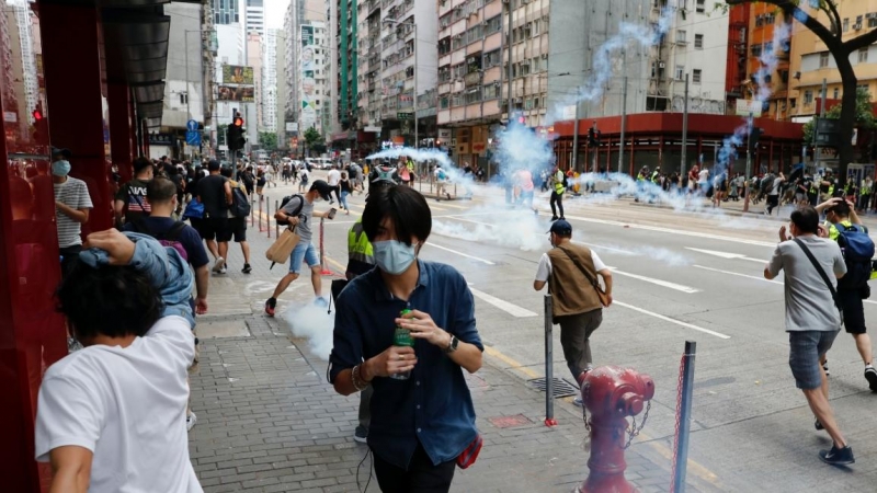 Los manifestantes antigubernamentales reaccionan cuando la policía antidisturbios dispara gases lacrimógenos para dispersarlos durante una marcha contra los planes de Beijing de imponer legislación de seguridad nacional. REUTERS / Tyrone Siu