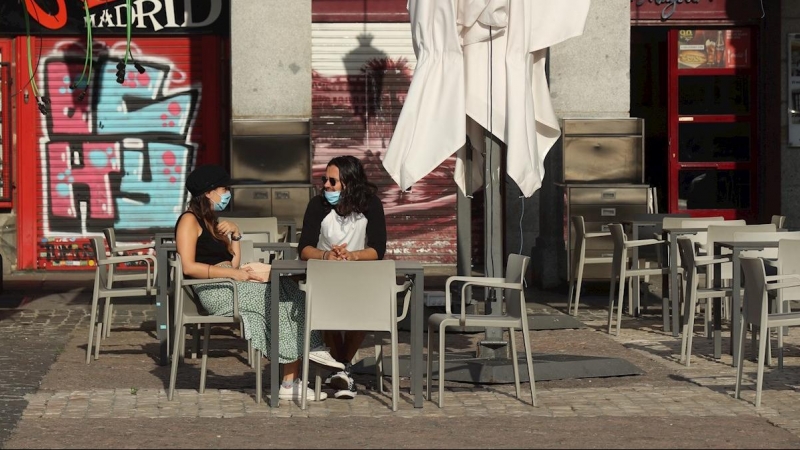 Dos personas esperan su consumición en una terraza de un bar de la Plaza Mayor en Madrid este lunes, donde comienza la fase 1 en la que la reapertura de las terrazas de los bares a un 50 % de su aforo y el acceso a los grandes parques son dos las principa