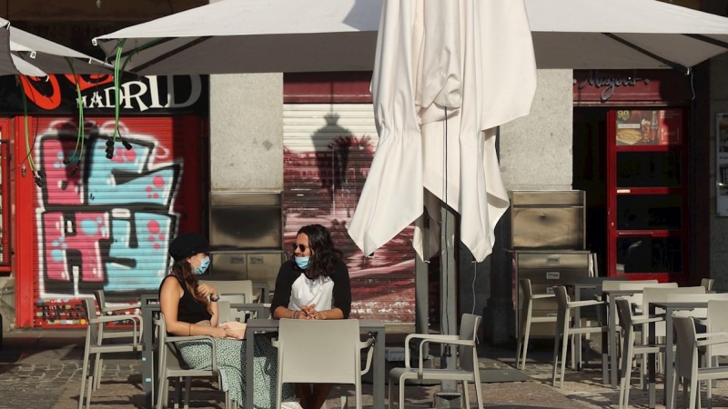 Dos personas esperan su consumición en una terraza de un bar de la Plaza Mayor en Madrid este lunes, donde comienza la fase 1 en la que la reapertura de las terrazas de los bares a un 50 % de su aforo y el acceso a los grandes parques son dos las principa