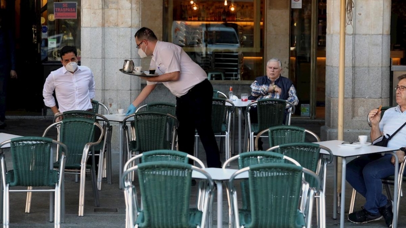 25/05/2020.- Un camarero sirve a los clientes en su bar de la Plaza Mayor de Salamanca este lunes durante el primer día de la fase 1 en la ciudad cuando las terrazas de los bares tienen su capacidad al 50 % y se permite el acceso a los grandes parques. EF