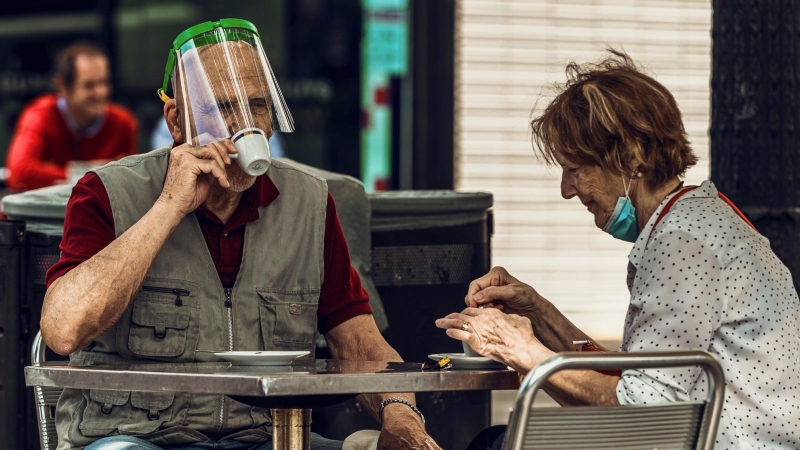 Un home amb un plàstic protector beu cafè en una terrassa d'un bar de la Plaça Catalunya de Barcelona. Matthias Oesterle/ZUMA Wire/dpa