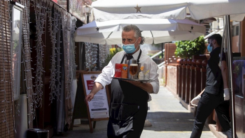 27/05/2020.- Un camarero lleva su pedido a unos clientes a una de las terrazas del Puerto Olímpico de Barcelona. / EFE